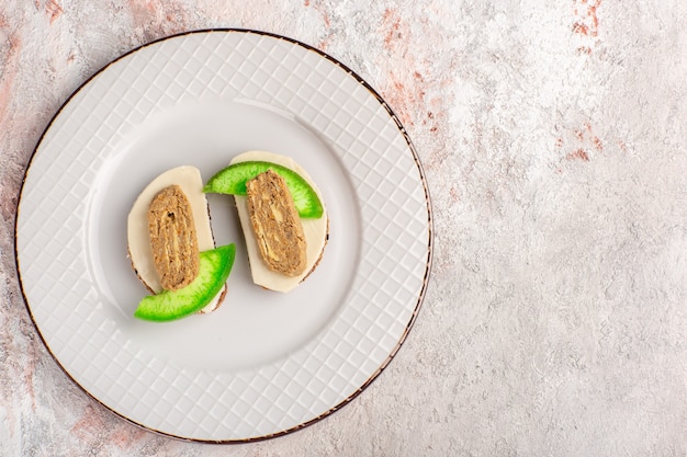 Foto grátis vista de cima torradas de pão com patê e fatias de pepino dentro do prato na parede branca carne comida vegetal sanduíche torrada