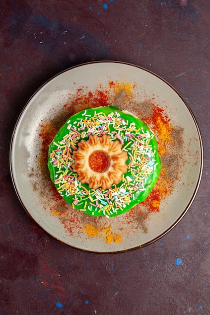 Vista de cima um pequeno bolo delicioso com creme verde na superfície escura