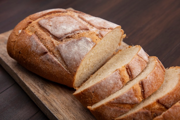 Vista de close-up de pão crocante cortado e fatiado em uma tábua em fundo de madeira