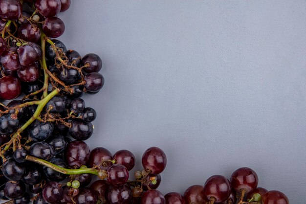 Vista de close-up de uvas pretas e vermelhas em fundo cinza