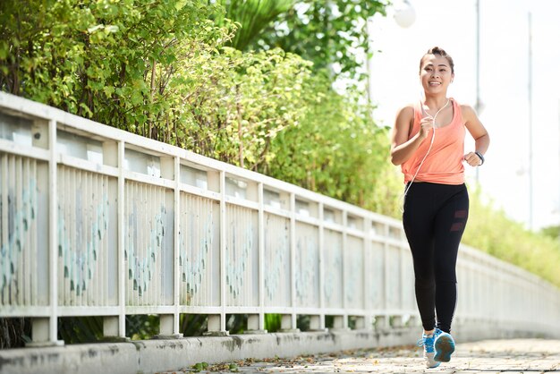 Vista de corpo inteiro do jovem atleta fazendo uma corrida matinal sozinha