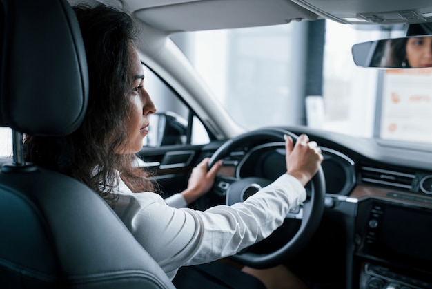 Vista de dentro. linda empresária testando seu novo carro no salão automóvel