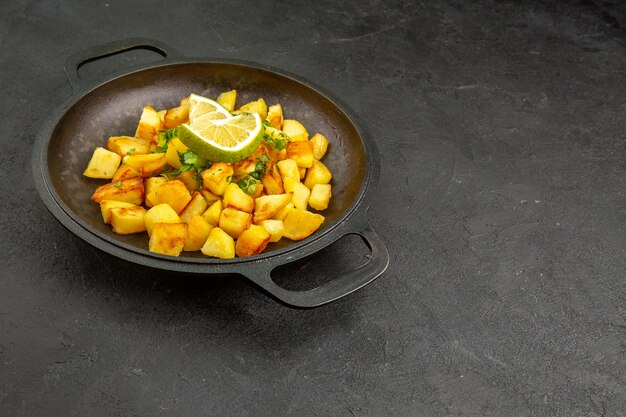 Foto grátis vista de frente saborosas batatas fritas dentro de uma panela com rodelas de limão na mesa escura