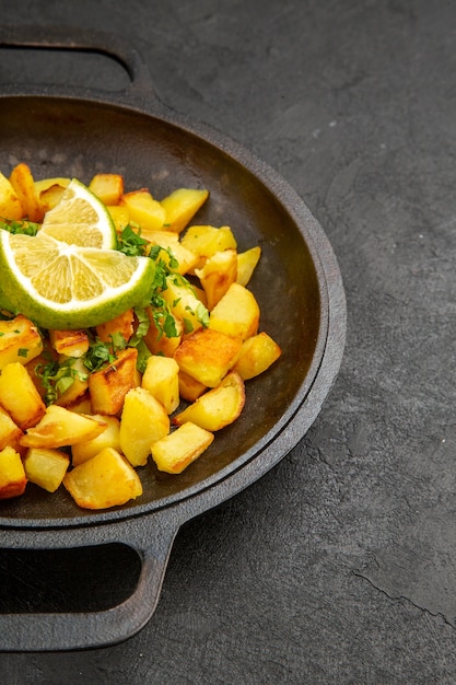 Foto grátis vista de frente saborosas batatas fritas dentro de uma panela com rodelas de limão na mesa escura