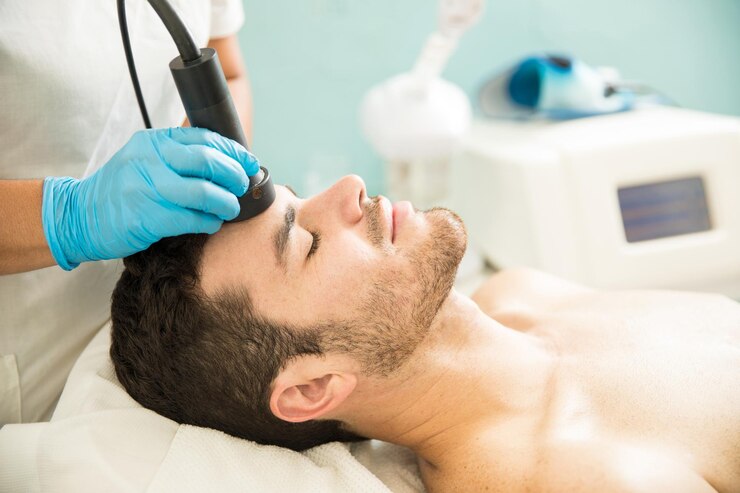 Foto grátis vista de perfil de um jovem bonito recebendo um tratamento facial rf em um spa de saúde