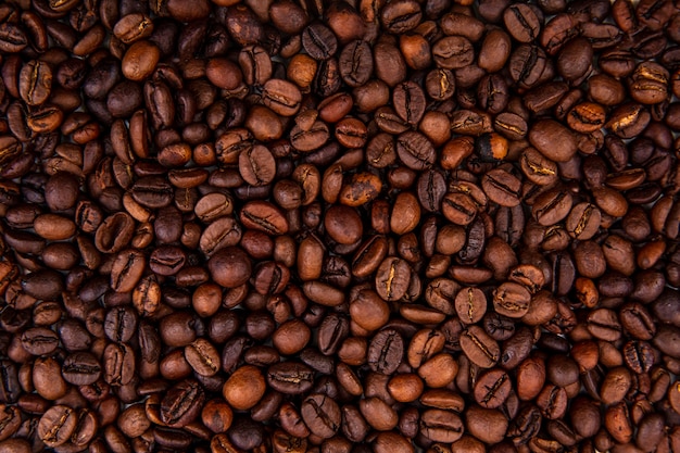 Vista de perto de grãos de café torrados frescos e escuros em fundo de grão de café