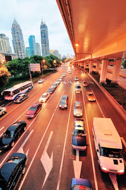 Vista de rua de Xangai com cena urbana e tráfego movimentado ao entardecer.