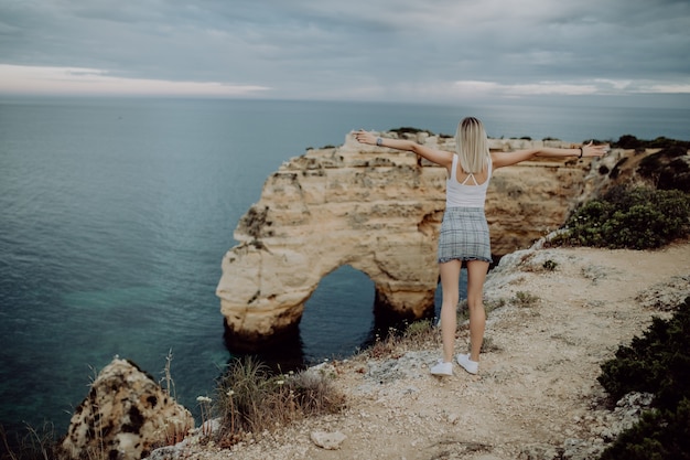 Vista de trás. Uma jovem turista aprecia as belas vistas do Oceano Atlântico