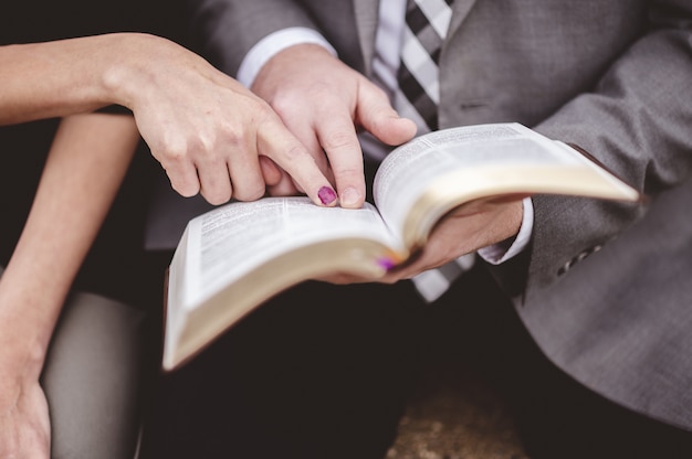 Foto grátis vista de um casal lendo um livro juntos enquanto aponta uma parte em uma página