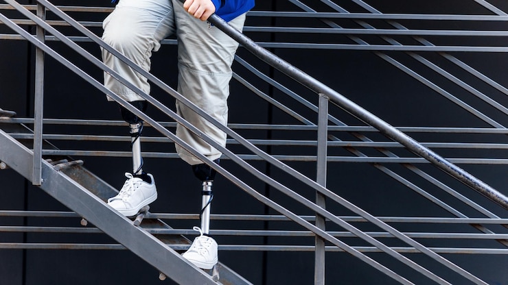 Foto grátis vista de um homem com pernas protéticas e tênis branco em uma escada de metal