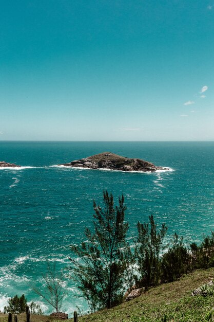 Vista de um penhasco com uma pequena ilha cercada pelo mar em um cenário de céu claro