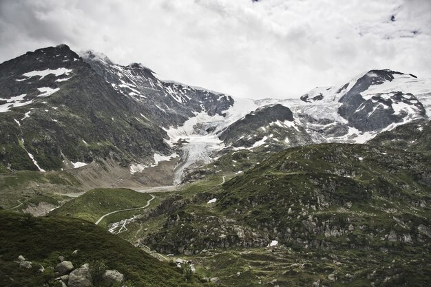 Vista de uma estrada estreita cercada por altas montanhas cobertas de neve no topo