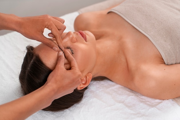 Vista de uma mulher recebendo uma massagem facial de ioga para se manter jovem