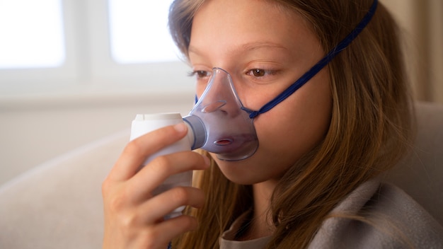 Vista do adolescente usando nebulizador em casa para problemas de saúde respiratória