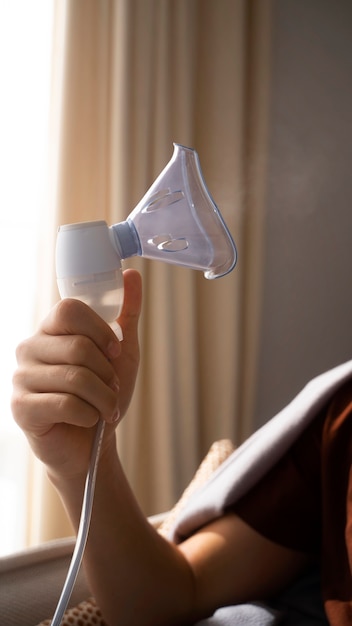 Vista do adolescente usando nebulizador em casa para problemas de saúde respiratória