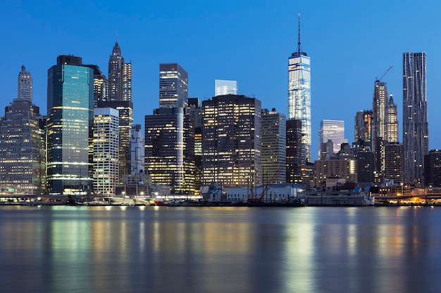 Vista do centro de Manhattan em Nova York ao anoitecer com arranha-céus iluminados sobre o East River