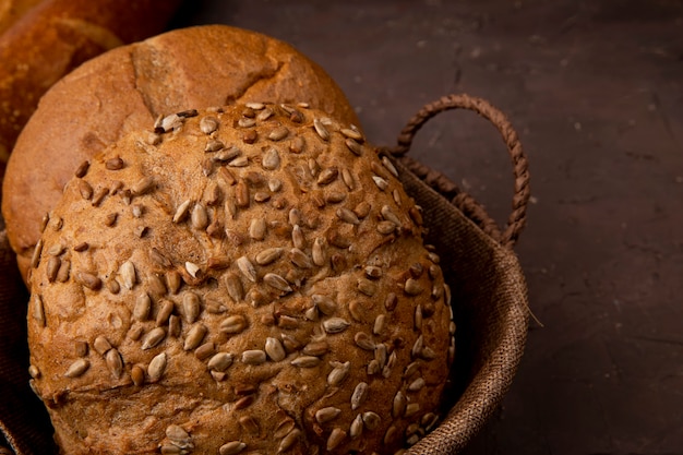 Vista do close-up da cesta de pães de espiga clássicos e semeados em fundo marrom com espaço de cópia