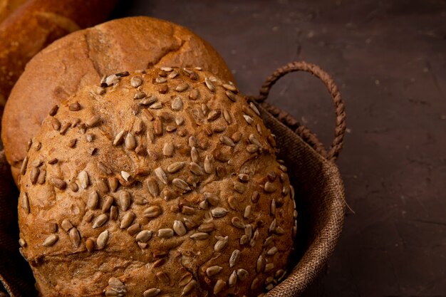 Vista do close-up da cesta de pães de espiga clássicos e semeados em fundo marrom com espaço de cópia