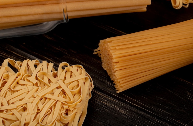 Vista do close-up de macaronis como espaguete de tagliatelle bucatini na mesa de madeira