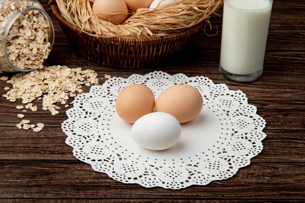 Vista do close-up de ovos na superfície de guardanapo de papel com flocos de aveia e leite no fundo de madeira
