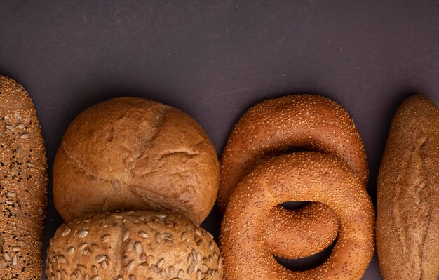 Vista do close-up de pães como baguete de baguete de espiga no fundo marrom com espaço de cópia