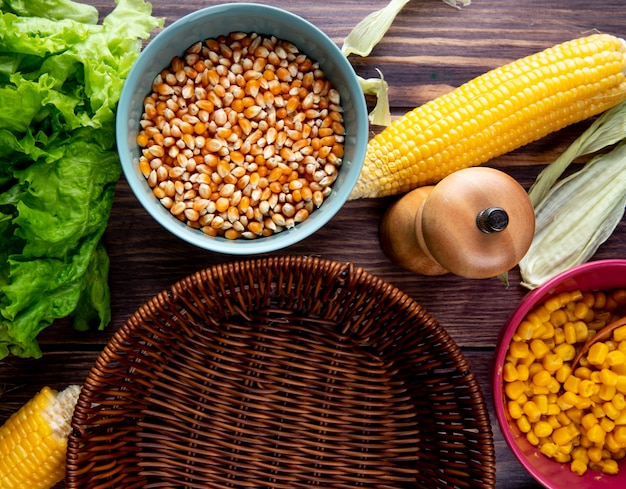 Foto grátis vista do close-up de sementes de milho com grãos de alface e cesto vazio na mesa de madeira