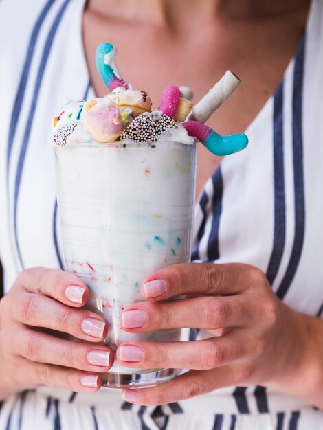 Vista do close-up de uma mulher segurando um copo de milk-shake