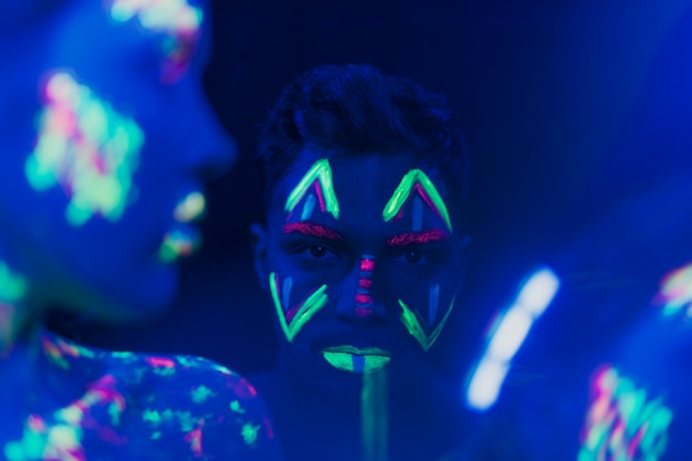 Vista do close-up do homem com maquiagem fluorescente