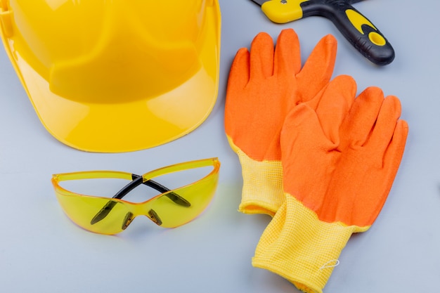 Vista do close-up do padrão do conjunto de ferramentas de construção, como óculos de segurança, capacete de segurança, espátula e luvas em fundo cinza