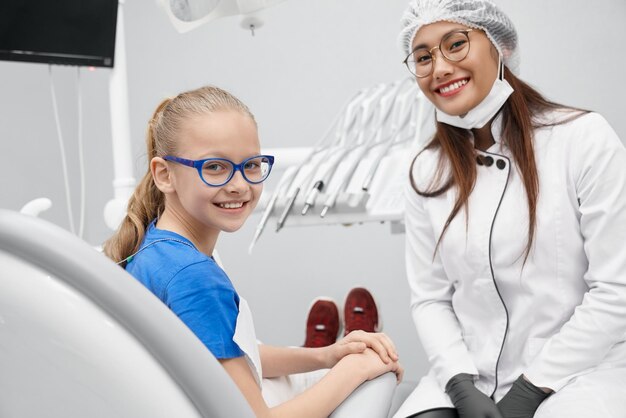 Vista do lado da garota feliz sentada no consultório do dentista