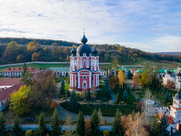 Vista do Mosteiro Curchi do drone. Igrejas, outros edifícios, relvados verdes e caminhos pedonais. Colinas com vegetação ao longe. Moldova