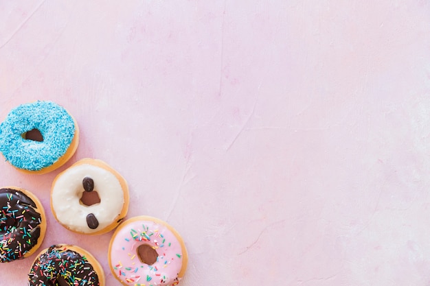 Vista elevada de deliciosos donuts no pano de fundo rosa