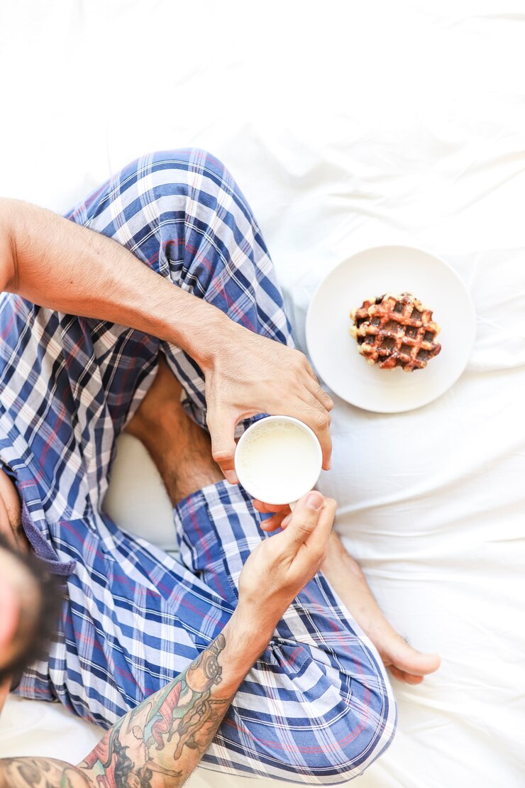 Foto grátis vista elevada, de, homem, com, xícara leite, e, waffle, sentar cama