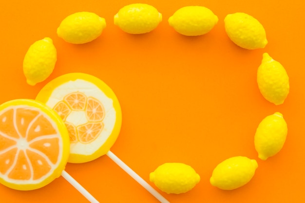 Vista elevada de pirulitos cítricos e doces de limão na superfície laranja