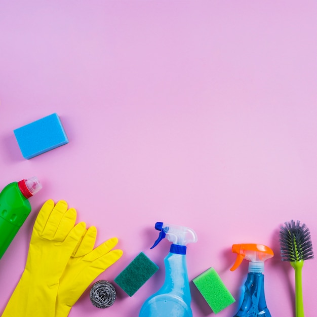 Vista elevada de produtos de limpeza em fundo rosa