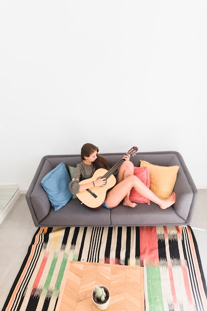 Foto grátis vista elevada, de, relaxado, menina adolescente, sentar sofá, violão jogo