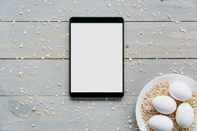Vista elevada, de, tablete digital, com, ovos, e, aveia, ligado, prato