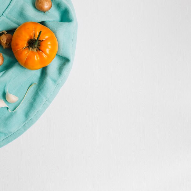 Vista elevada de tomate; cebola e alho na superfície branca