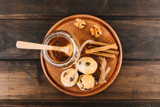Vista elevada do mel; noz; especiarias e cup cakes em fundo de madeira