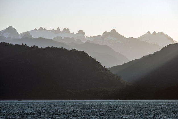 Vista fascinante das silhuetas das montanhas atrás do oceano calmo durante o pôr do sol