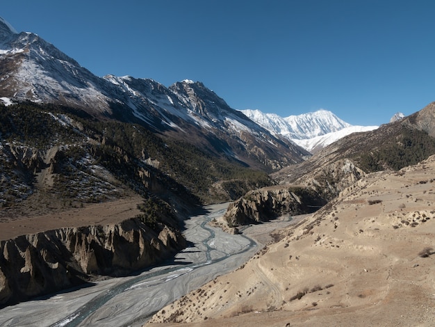 Vista fascinante dos riachos de água pelas montanhas cobertas de neve no Nepal