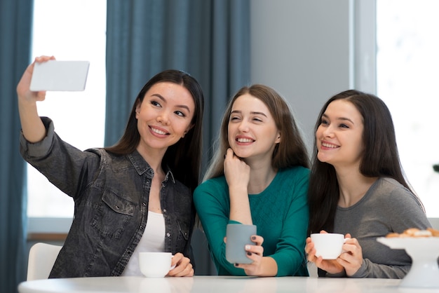 Vista frontal adoráveis jovens mulheres tomando uma selfie juntos