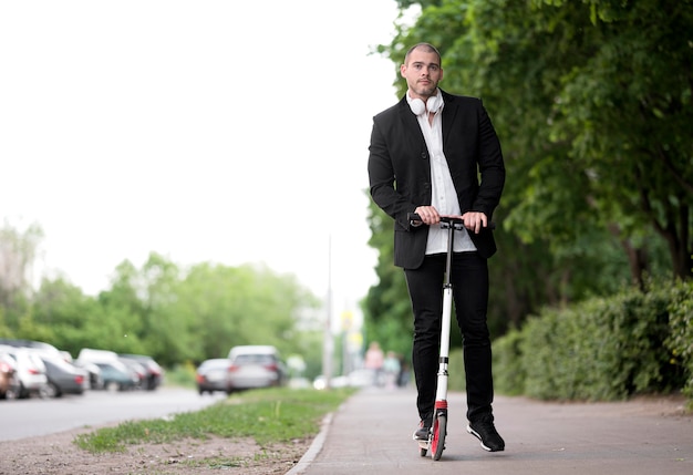 Vista frontal adulto masculino andar de scooter ao ar livre