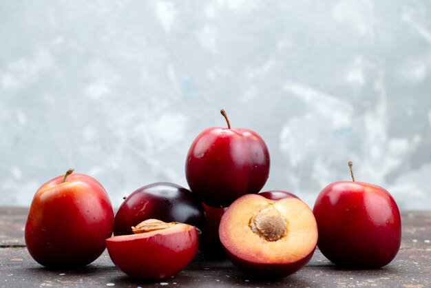 Vista frontal ameixas azedas frescas suculentas e maduras em madeira escura, árvore azeda de verão frutas