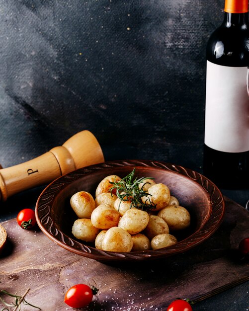 Vista frontal batata frita pouco junto com tomate vermelho e vinho tinto na superfície cinza