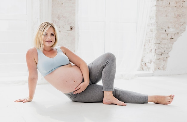 Vista frontal bonita mulher grávida fazendo meditando