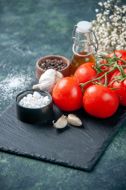 Vista frontal close-up tomates vermelhos frescos com temperos na superfície escura refeição comida saúde dieta salada