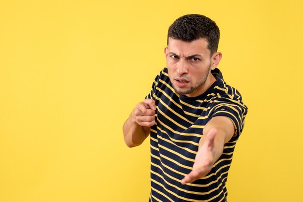 Vista frontal confuso jovem em camiseta listrada preto e branco amarelo isolado fundo espaço livre