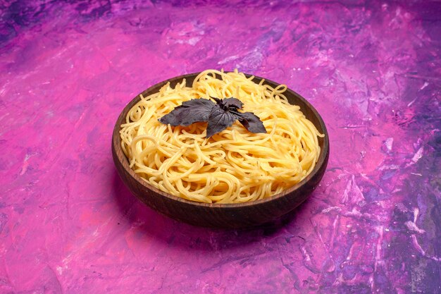 Vista frontal cozido delicioso espaguete dentro do prato em um prato de massa de massa de mesa rosa