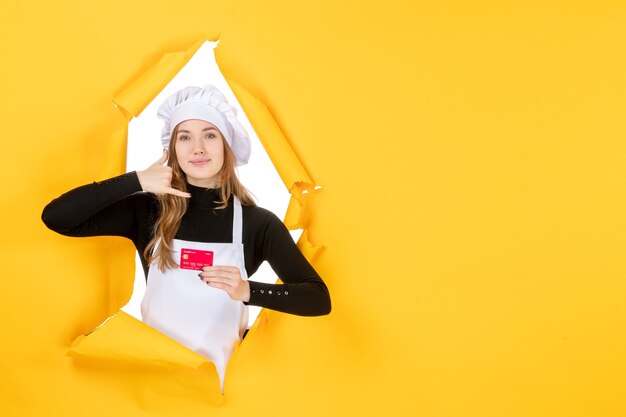 Vista frontal cozinheira segurando um cartão de banco vermelho em amarelo trabalho foto emoção comida cozinha cor dinheiro cozinha